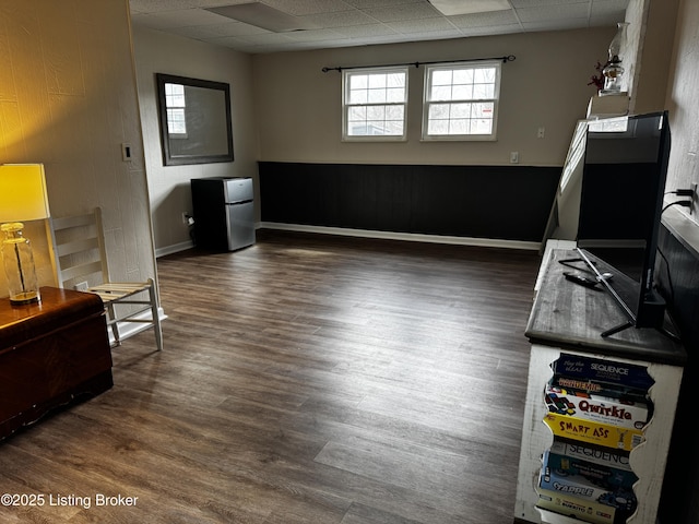 interior space with a paneled ceiling and dark hardwood / wood-style floors