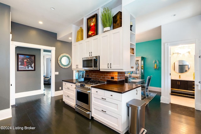 kitchen with appliances with stainless steel finishes, backsplash, white cabinets, and dark hardwood / wood-style flooring