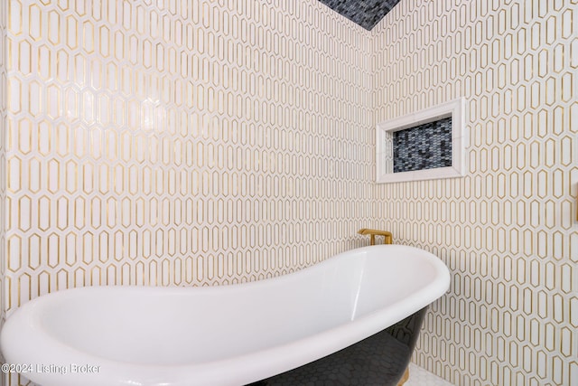 bathroom featuring a tub to relax in and tile walls