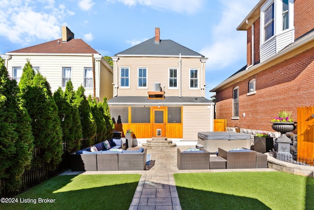 back of house with a yard, an outdoor hangout area, a covered hot tub, and a patio area