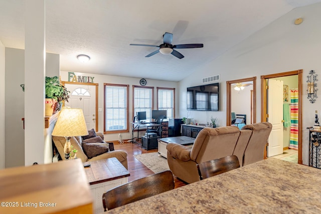 living room with vaulted ceiling, ceiling fan, and light wood-type flooring