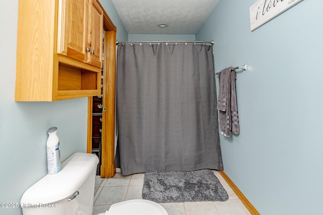 bathroom with tile patterned floors, toilet, curtained shower, and a textured ceiling