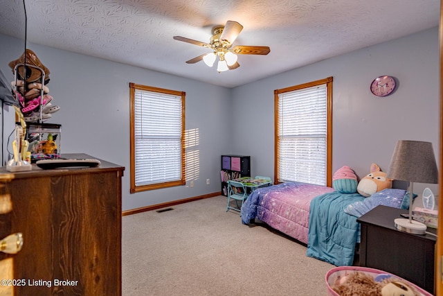 bedroom featuring ceiling fan, light colored carpet, and a textured ceiling