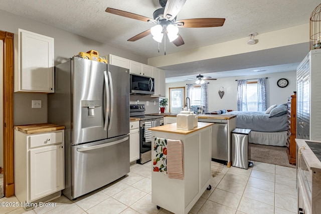 kitchen featuring white cabinetry, stainless steel appliances, butcher block countertops, and light tile patterned floors