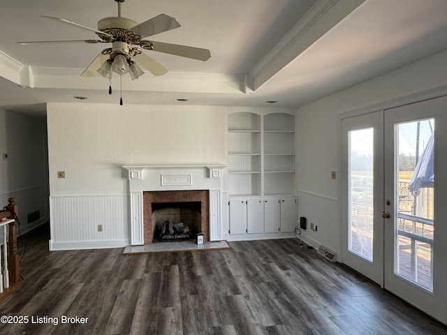 unfurnished living room featuring french doors, dark hardwood / wood-style floors, a raised ceiling, a tile fireplace, and built in features