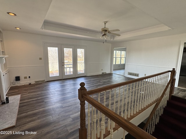 interior space featuring dark wood-type flooring, a raised ceiling, and ceiling fan