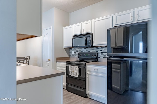 kitchen with backsplash, black appliances, white cabinets, and light wood-type flooring