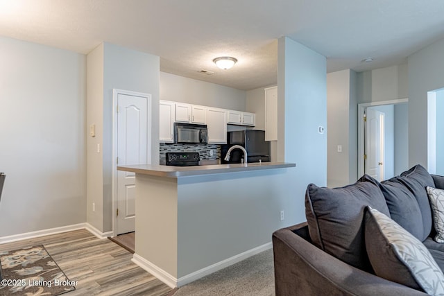 kitchen featuring white cabinetry, tasteful backsplash, black appliances, and kitchen peninsula