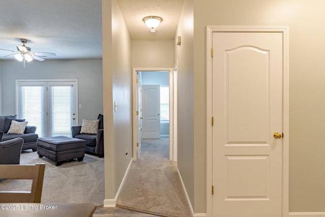 hall with light carpet and a textured ceiling