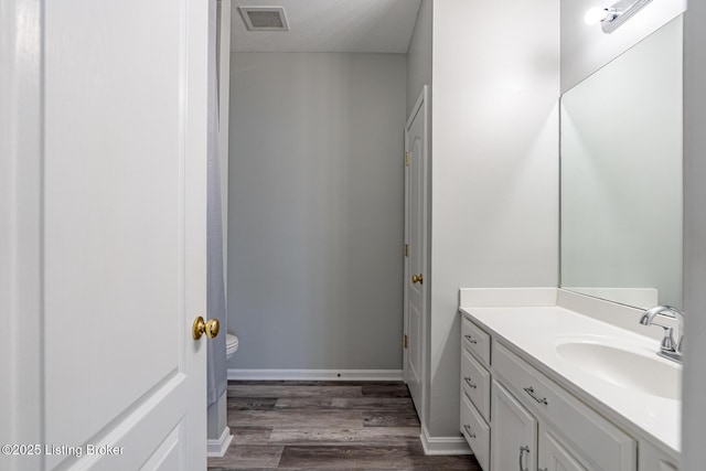 bathroom featuring vanity, toilet, hardwood / wood-style floors, and a textured ceiling