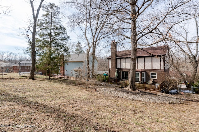 back of property with a chimney, fence, and brick siding