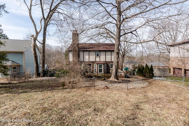 view of front of house with a deck, a chimney, and fence