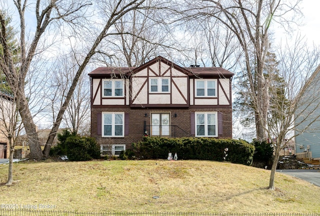 english style home with a front yard, brick siding, and stucco siding