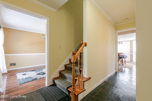 staircase with crown molding, baseboards, visible vents, and stone tile floors