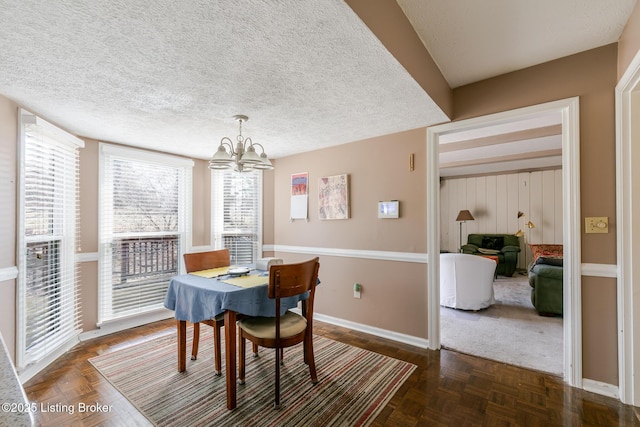 dining room with a notable chandelier, baseboards, and a textured ceiling