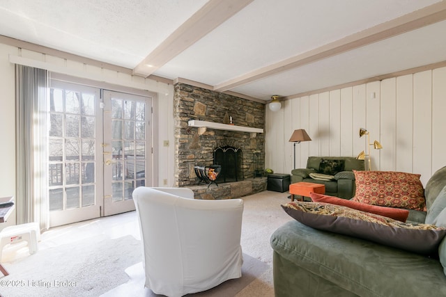 living area with a textured ceiling, a stone fireplace, light carpet, french doors, and beam ceiling