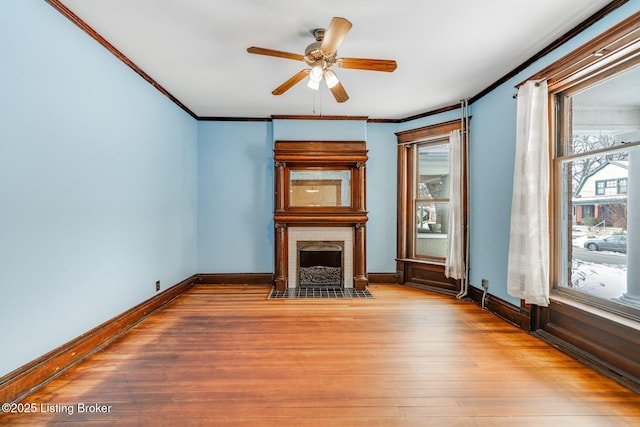 unfurnished living room featuring wood finished floors, baseboards, a fireplace with flush hearth, and ornamental molding