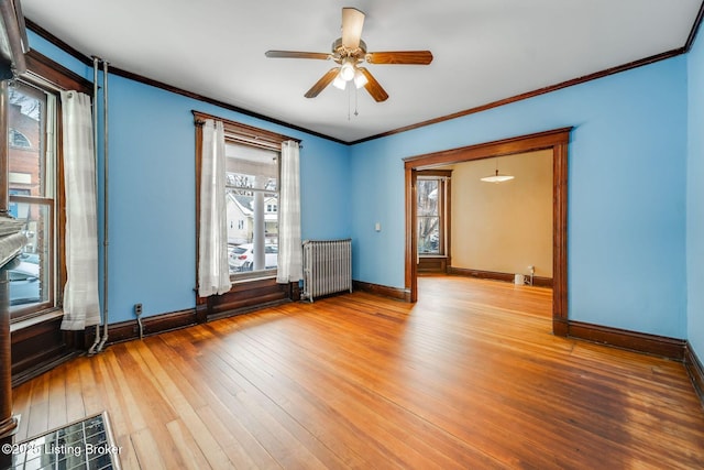 empty room with crown molding, radiator heating unit, baseboards, and hardwood / wood-style floors