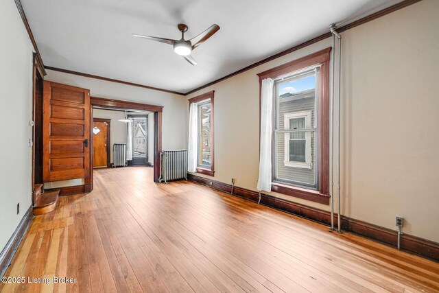 unfurnished room featuring baseboards, radiator, light wood-style flooring, and ornamental molding