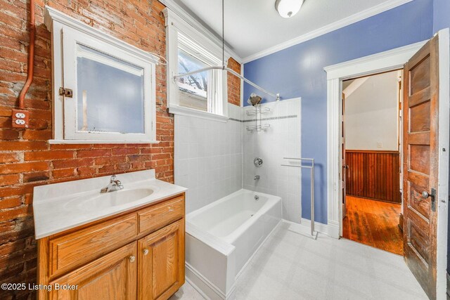 bathroom with vanity, washtub / shower combination, brick wall, ornamental molding, and wainscoting