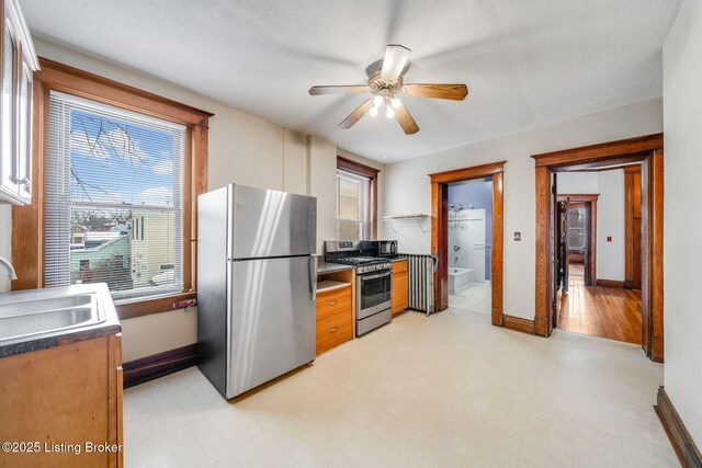 kitchen featuring ceiling fan, light floors, appliances with stainless steel finishes, and a sink