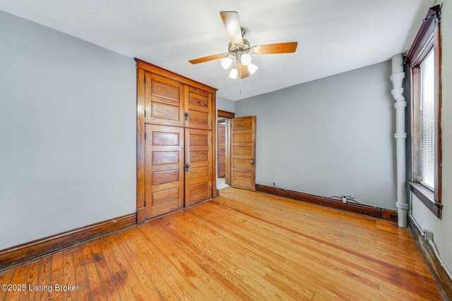 unfurnished bedroom with baseboards, light wood-style floors, and a ceiling fan