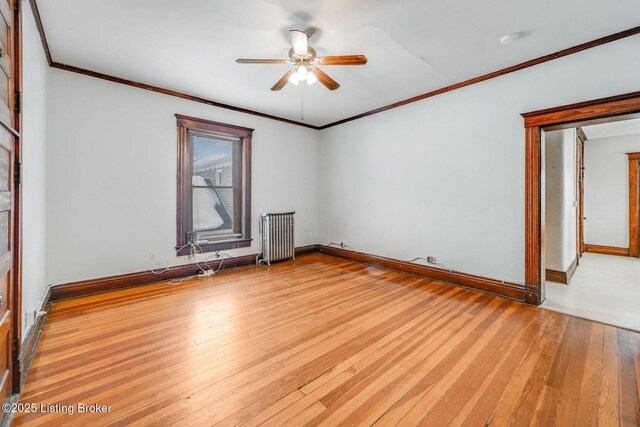 empty room with wood finished floors, radiator, crown molding, baseboards, and ceiling fan