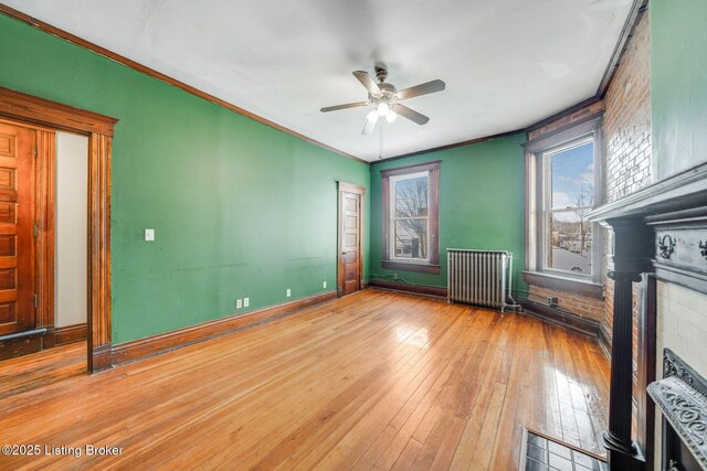 unfurnished living room with a fireplace with flush hearth, wood-type flooring, radiator heating unit, and crown molding