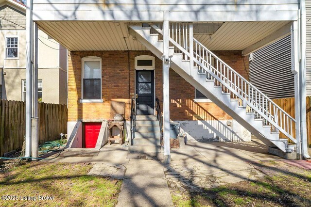 entrance to property featuring brick siding and fence