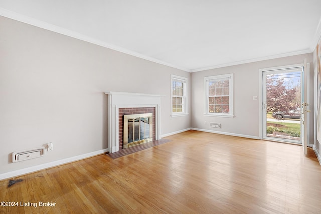 unfurnished living room featuring a brick fireplace, crown molding, and light hardwood / wood-style floors