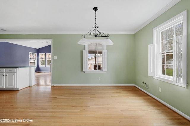 unfurnished dining area featuring crown molding and light wood-type flooring