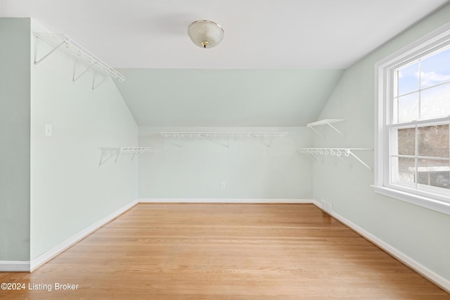 walk in closet with vaulted ceiling and light hardwood / wood-style flooring