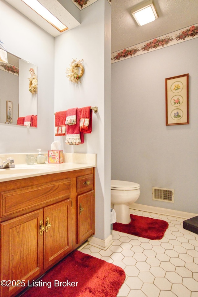 bathroom with vanity, toilet, and a textured ceiling