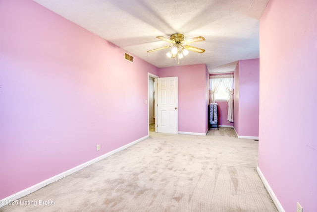 unfurnished bedroom with ceiling fan, light carpet, and a textured ceiling