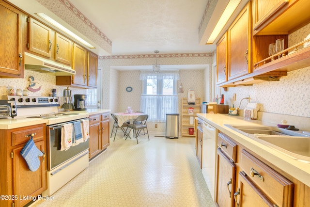 kitchen featuring sink, white appliances, and decorative light fixtures