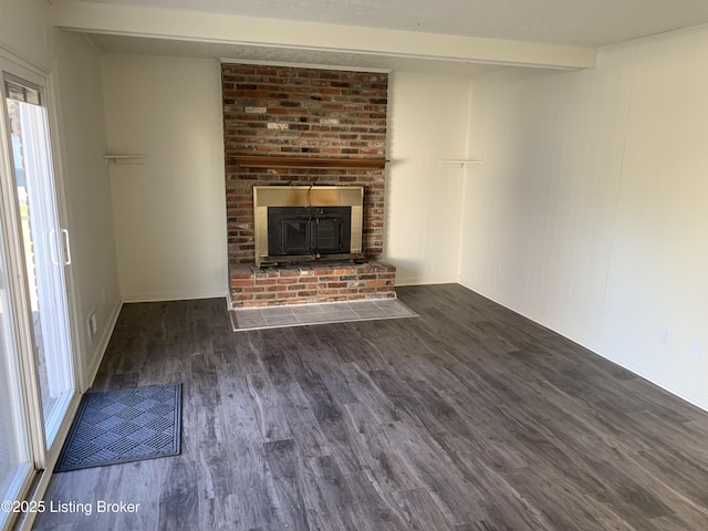 unfurnished living room featuring beam ceiling, dark wood-type flooring, and a healthy amount of sunlight