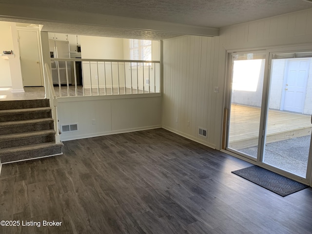 unfurnished living room with plenty of natural light, dark wood-type flooring, and a textured ceiling