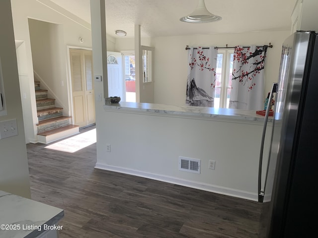 kitchen with dark wood-type flooring, stainless steel fridge, and a textured ceiling