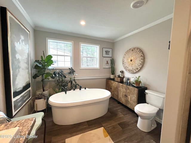 bathroom featuring crown molding, hardwood / wood-style flooring, vanity, a bath, and toilet