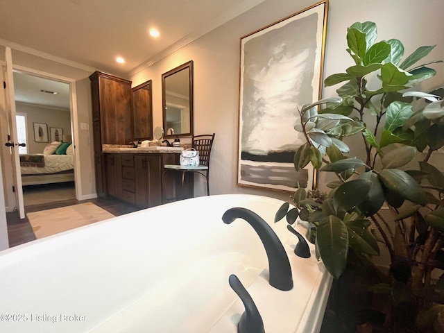 bathroom with ornamental molding, a bathing tub, and vanity