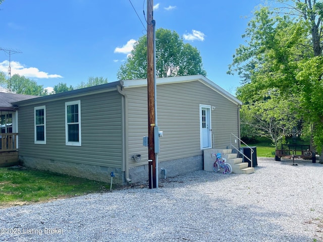 view of home's exterior featuring entry steps, driveway, and crawl space