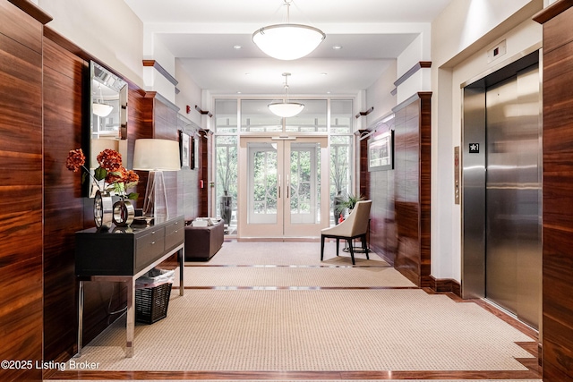 corridor featuring french doors, elevator, and light carpet