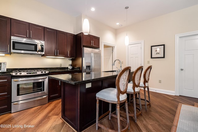 kitchen with sink, a breakfast bar area, a center island, pendant lighting, and stainless steel appliances