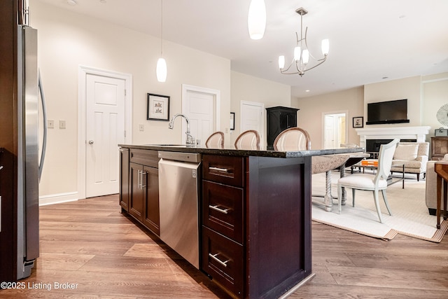 kitchen with pendant lighting, stainless steel appliances, sink, and an island with sink