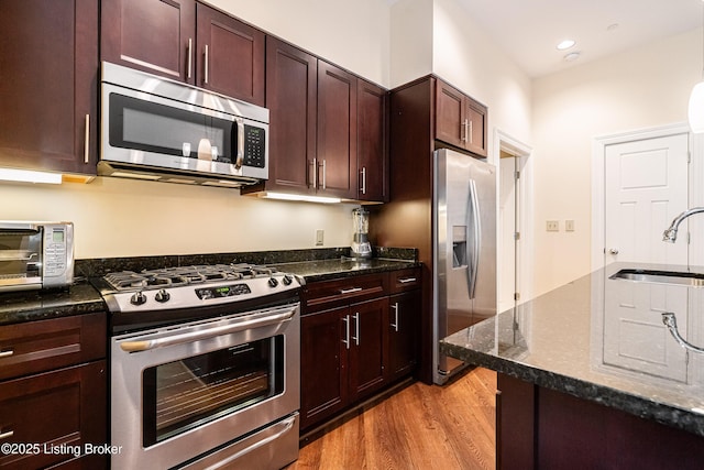 kitchen with sink, dark stone counters, and appliances with stainless steel finishes