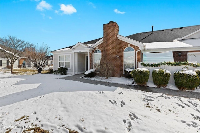 view of front facade with a chimney and brick siding