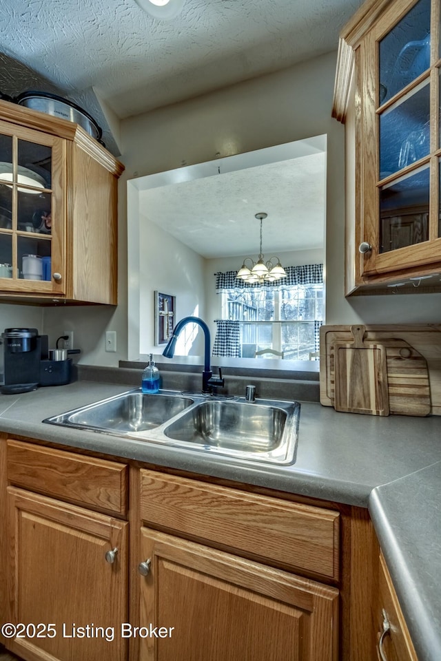 kitchen with an inviting chandelier, sink, pendant lighting, and a textured ceiling