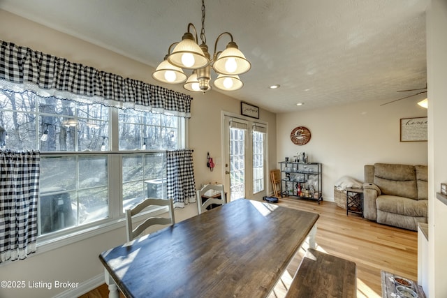 dining space featuring wood-type flooring and ceiling fan with notable chandelier