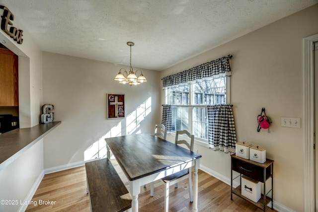 dining space featuring a chandelier, light hardwood / wood-style floors, and a textured ceiling