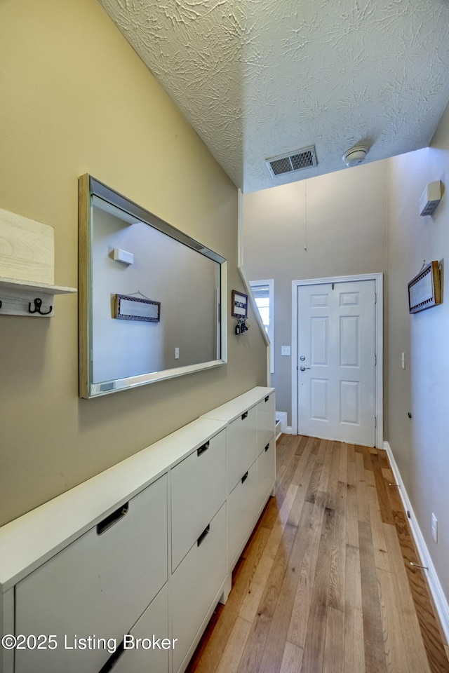 entryway with a textured ceiling and light hardwood / wood-style floors